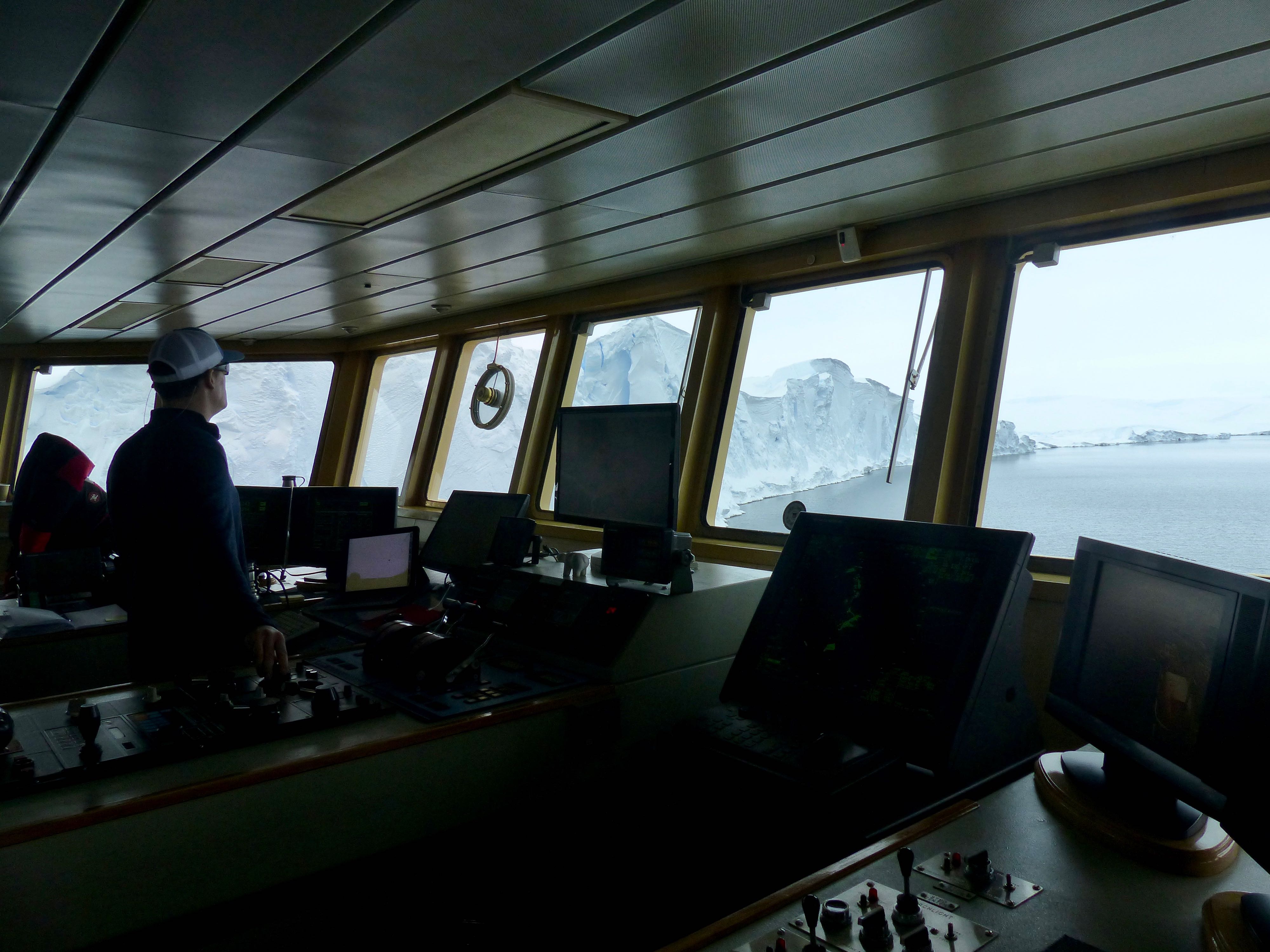 On the bridge of the ship, Luke Zeller, the third mate onboard the Palmer, navigates the ship a few hundred meters from the Thwaites ice front. As directed by the THOR's multibeam experts, he manuevers the ship so that the multibeam can map along the entire Thwaites ice front and as much as a kilometer underneath. Photo credit: Tasha Snow