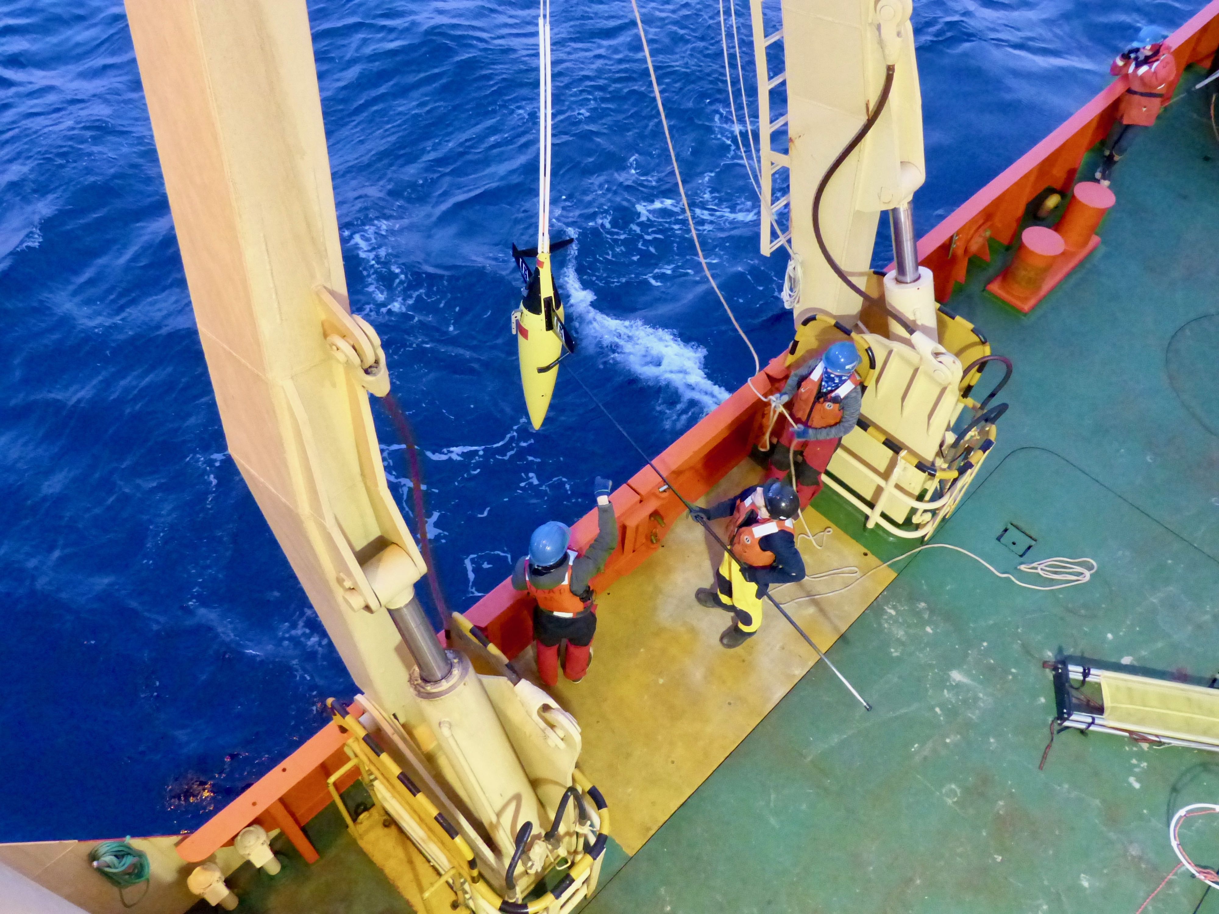 TARSAN scientist, Bastien Queste from the University of East Anglia (middle), deploys the ocean glider over the side of the Palmer with the assistance of Carmen Greto (left) and Jennie Mowatt (right). The glider conducted measurements for the next three days until it was recovered by the ship.