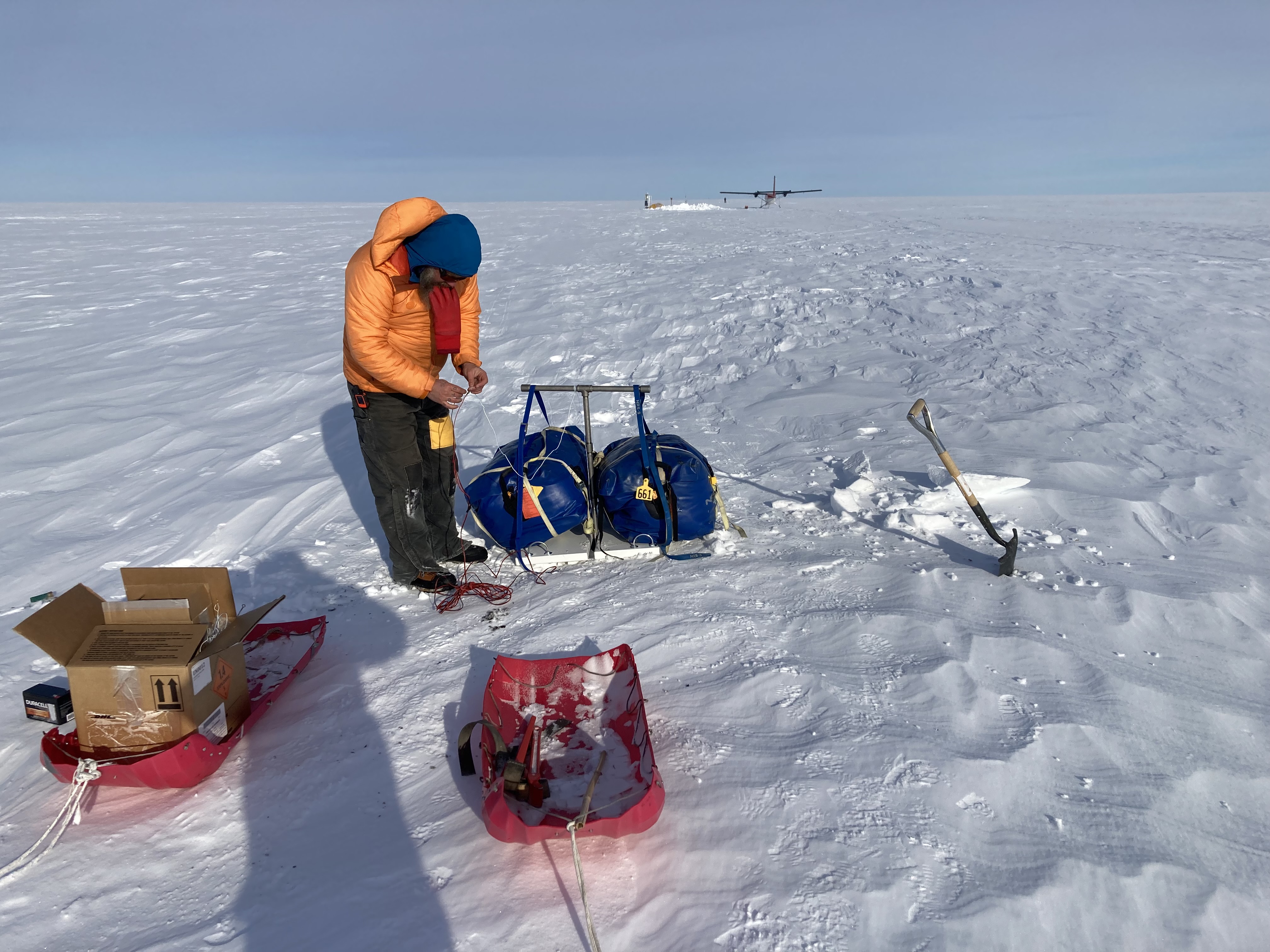 Figure 9.  Preparing a Betsy seismic source "shot" during a Distributed Acoustic Sensing (DAS) vertical seismic profile survey. The DAS measures strain on a fiber-optic cable that extends from the AMIGOS station through more than 200 m of ice, and another 600 m to the ocean floor. (C. Kratt)