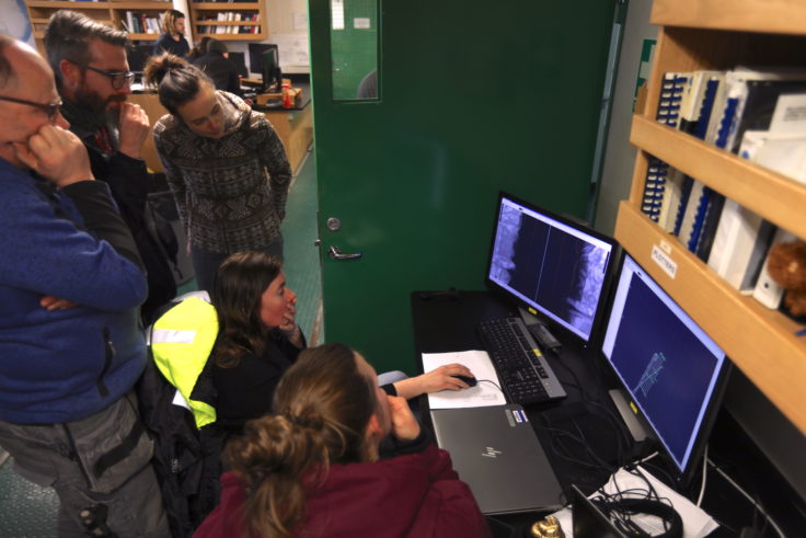 Scientists on the RV Nathaniel B Palmer analyse the side view of scans collected by Ran. Photo credit: Ali Graham