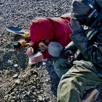 Victoria Fitzgerald records sample information about the shell fragment she just found while digging into a raised beach with a spoon. Carolyn Beeler, a radio reporter from BBC's The World (right), takes an audio recording of the find. Photo credit: Tasha Snow