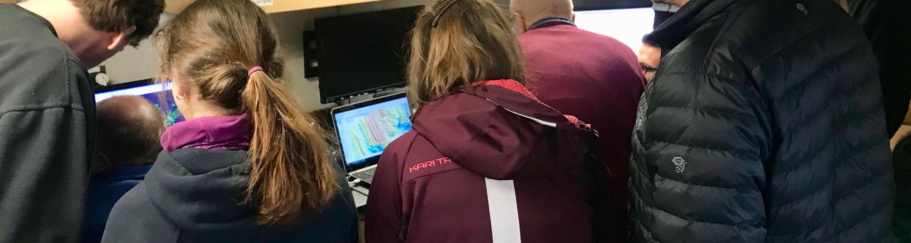Scientists gather around computers to learn the latest discoveries about the Thwaites Glacier ice shelf.